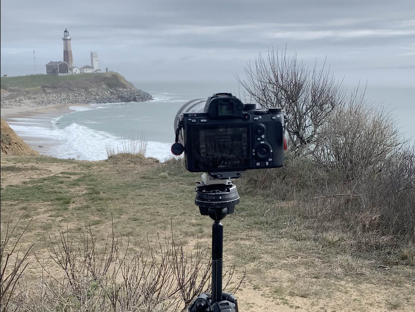 A camera on a tripod taking a time lapse or hyperlapse of a lighthouse in Montauk, New York.